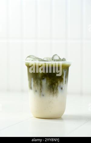 Latte freddo Matcha in vetro monouso in plastica con tè verde Matcha sul latte o latte vegetale Foto Stock