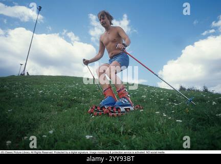 Slalom senza neve. Nel 1980 una nuova invenzione degli sci d'erba è in fase di sperimentazione, in estate. Gli sci sono costruiti con nastri rotanti e hanno funzionalità simili a quelle degli sci normali. Nella foto un uomo che prova gli sci rotolanti in estate su una collina ricoperta di erba. C'erano una manciata di produttori di sci d'erba negli anni '1980 Ecco una pagina web che racconta la storia dello sci d'erba: https://www.theskijournal.com/exclusive/grassholes/ rif. DV25 Foto Stock