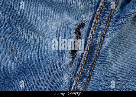 vecchi jeans strappati da usura frequente, jeans danneggiati con un foro nel tessuto adatto per la riparazione e le cuciture Foto Stock