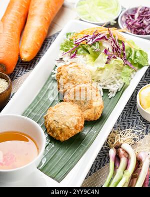 Gnocchi fritti dorati croccanti serviti su una foglia di banana con insalata fresca e un contorno di salsa per immersione: Un'irresistibile fusione di croccante e sapore! Foto Stock