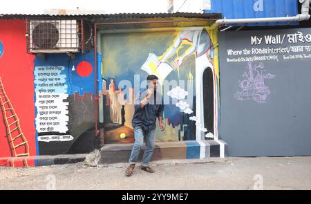 Kolkata, India. 20 dicembre 2024. Un uomo parla sul suo cellulare di fronte a un murale all'interno di un vicolo durante un festival d'arte all'aperto, il Behala Art Fest, a Kolkata, in India, il 20 dicembre 2024. (Foto di Rupak De Chowdhuri/NurPhoto) crediti: NurPhoto SRL/Alamy Live News Foto Stock