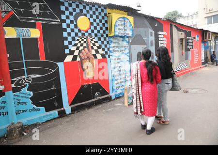 Kolkata, India. 20 dicembre 2024. Le donne camminano davanti a un murale all'interno di un vicolo durante un festival d'arte all'aperto, il Behala Art Fest, a Kolkata, in India, il 20 dicembre 2024. (Foto di Rupak De Chowdhuri/NurPhoto) crediti: NurPhoto SRL/Alamy Live News Foto Stock