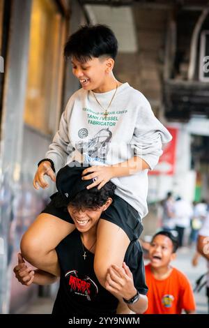 I ragazzi filippini lottano per far cadere la palla da un muro alto. Giocano per le strade di China Town nel quartiere Binondo di Manila. Foto Stock