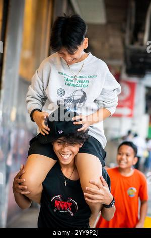 I ragazzi filippini lottano per far cadere la palla da un muro alto. Giocano per le strade di China Town nel quartiere Binondo di Manila. Foto Stock