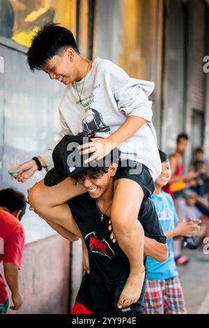 I ragazzi filippini lottano per far cadere la palla da un muro alto. Giocano per le strade di China Town nel quartiere Binondo di Manila. Foto Stock