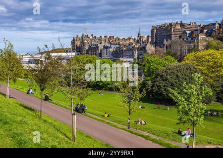 Città di Edimburgo in Scozia, Regno Unito. Le persone si rilassano sull'erba nei Princes Street Gardens nel soleggiato pomeriggio primaverile con vista sulla città vecchia. Foto Stock