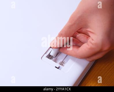 Donna che inserisce le batterie in un dispositivo Foto Stock