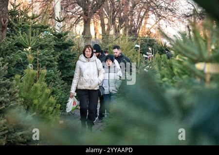 ODESA, UCRAINA - 19 DICEMBRE 2024 - le persone passano davanti agli alberi di Natale venduti in una strada locale, Odesa, Ucraina meridionale Foto Stock