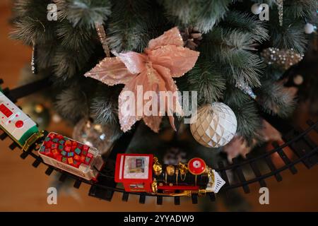 Un albero di Natale splendidamente decorato e decorato che presenta ornamenti colorati e un affascinante trenino giocattolo Foto Stock