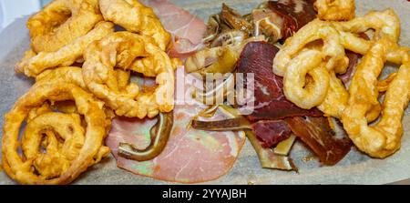 Un piatto colorato mostra un assortimento di affettati e spuntini croccanti. La combinazione mette in mostra sapori tipici di una prelibatezza regionale, in Foto Stock
