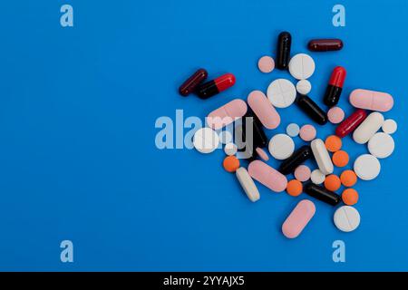 Una collezione di pillole colorate e capsule sparse su una superficie blu vibrante. Foto Stock