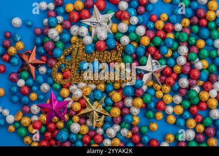 Una disposizione di palline glitter multicolore abbinate a stelle decorative natalizie, su un vivace sfondo blu. Perfetto per l'holida Foto Stock