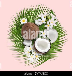 Noci di cocco, fiori tropicali e foglie su sfondo rosa Foto Stock