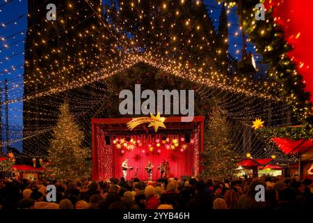 Colonia, Germania 20 dicembre 2024: Molti visitatori di fronte al palco di musica dal vivo presso il famoso mercatino di natale della cattedrale di colonia negli eveni Foto Stock