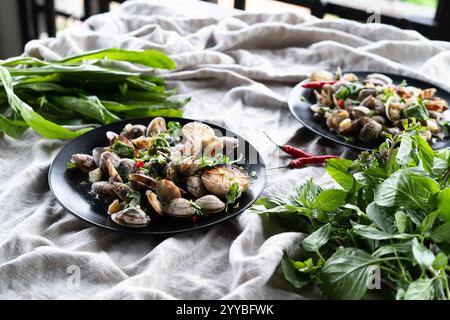 Le vongole e le cozze sono ben disposte su piatti, con erbe fresche e peperoncini. Foto Stock