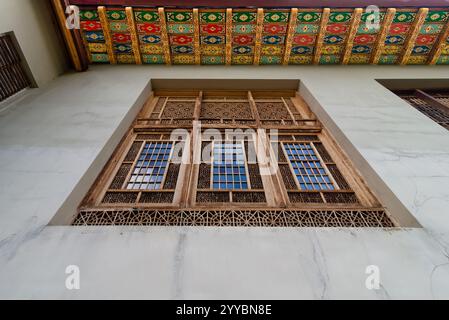 Un'intricata finestra di legno intagliata adorna il Palazzo Shakikhanovs a Shaki, Azerbaigian, ed è incorniciata da un vivace soffitto a motivi geometrici Foto Stock