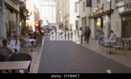 La scena di strada a marsiglia mostra persone sfocate, effetto bokeh, caffetterie che costeggiano la pietra acciottolata, catturando l'essenza di una vivace città europea con un Foto Stock