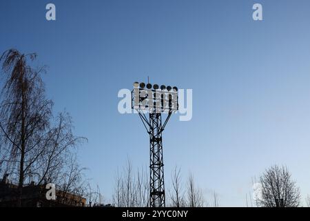 Un alto campo sportivo con torre faro che si erge maestosamente contro il cielo azzurro Foto Stock
