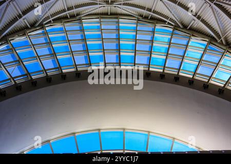 Il cielo blu si riflette nel soffitto di vetro di un edificio. La luce del sole splende attraverso le finestre, creando un'atmosfera luminosa e ariosa Foto Stock