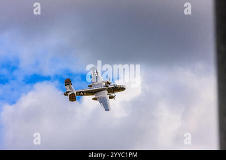 Un aereo con una croce sulla coda vola attraverso un cielo nuvoloso. Concetto di libertà e avventura, mentre l'aereo sorvola il cielo sopra le nuvole Foto Stock