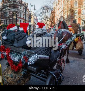 I viaggiatori sfilano attraverso il centro di Londra su carri trainati da cavalli durante il periodo festivo. Foto Stock