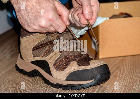 Le mani da uomo legano i lacci delle scarpe. Il concetto di montaggio di nuove scarpe. primo piano Foto Stock