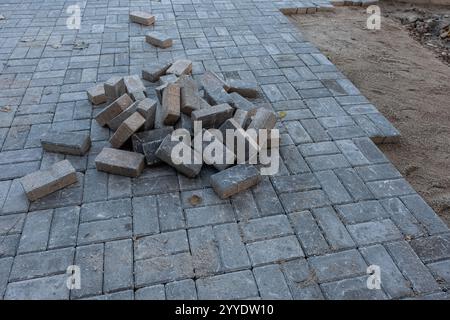 Cantiere. Pavimentazione di mattoni installati su un pedone. Posa di lastre e bordi per pavimentazione. Lavori stradali di posa di lastre di pavimentazione in calcestruzzo grigio. Processo di in Foto Stock