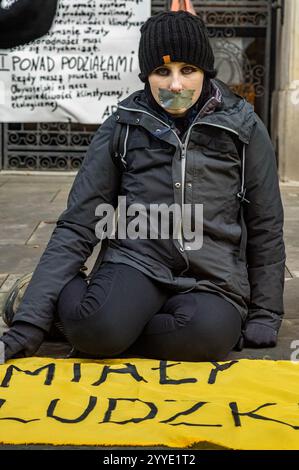 Un manifestante la cui bocca è fissata si siede davanti al manifesto e sopra uno striscione a terra durante la manifestazione. Gli attivisti del gruppo della ribellione degli animali spruzzarono e dipinsero le loro richieste sulle pareti del Ministero dell'Agricoltura e dello sviluppo rurale di Varsavia, attaccarono un manifesto al cancello, poi con la bocca chiusa, aspettarono silenziosamente l'arrivo della polizia. Il gruppo polacco per la ribellione degli animali ha dichiarato che tutti i materiali utilizzati nella protesta sono facilmente lavabili e non permanenti. L'intenzione dell'azione è di richiamare l'attenzione sulle sofferenze degli animali e del clima Foto Stock