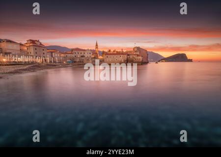 L'alba colorata sulla città vecchia di Budva e sull'isola di Sveti Nikola si riflette sul mare Adriatico, Montenegro Foto Stock