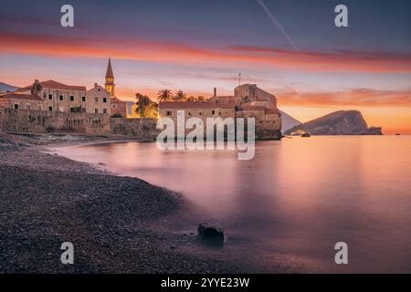 L'alba colorata sulla città vecchia di Budva e sull'isola di Sveti Nikola si riflette sul mare Adriatico, Montenegro Foto Stock