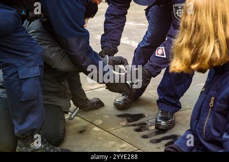 Gli agenti di polizia lottano con una bomboletta di vernice spray dalle mani di un manifestante durante la manifestazione. Gli attivisti del gruppo della ribellione degli animali spruzzarono e dipinsero le loro richieste sulle pareti del Ministero dell'Agricoltura e dello sviluppo rurale di Varsavia, attaccarono un manifesto al cancello, poi con la bocca chiusa, aspettarono silenziosamente l'arrivo della polizia. Il gruppo polacco per la ribellione degli animali ha dichiarato che tutti i materiali utilizzati nella protesta sono facilmente lavabili e non permanenti. L'obiettivo dell'azione è di richiamare l'attenzione sulle sofferenze degli animali e sul costo climatico di tali af industriali Foto Stock