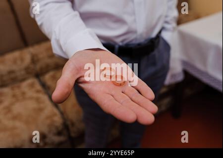 Eleganti anelli da sposa tenuti in mano a un uomo che simboleggiano l'amore e l'impegno. Foto Stock