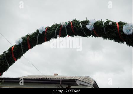 L'arcata festosa è decorata con vegetazione e nastri sotto il cielo nuvoloso. Foto Stock