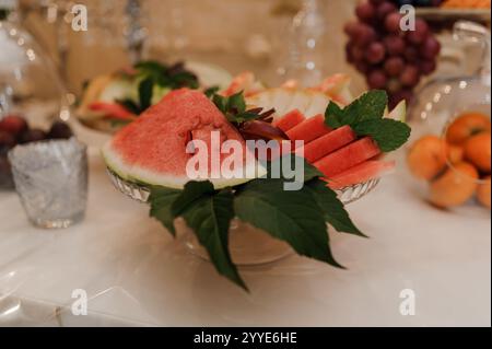 Anguria a fette fresche e frutta assortita su un elegante tavolo. Foto Stock