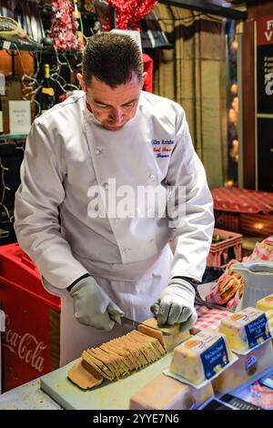 Strasburgo, Francia - 14 dicembre 2024: Il famoso Chef Gilles Reinhardt del ristorante Paul Bocuse serve panini di foie gras al mercato di Chrismas Foto Stock