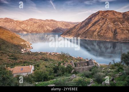 Splendida vista al tramonto della baia di Cattaro in Montenegro, con acque tranquille, montagne maestose e antiche rovine Foto Stock