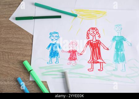 Disegno per bambini di una famiglia felice e penne in feltro su un tavolo in legno, vista dall'alto Foto Stock