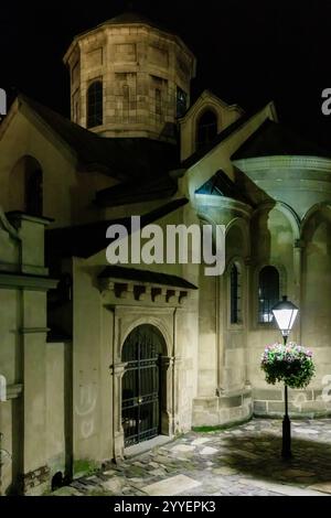 Una chiesa con un alto campanile e un lampione davanti ad essa. Il palo della lampada è illuminato di notte Foto Stock