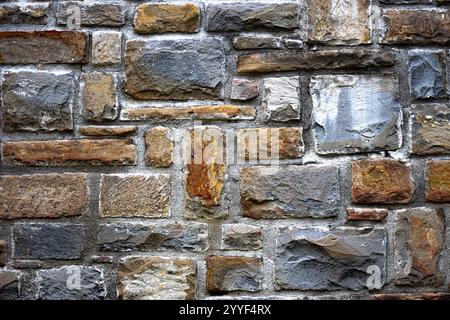 Un primo piano di un muro di pietra, costruito con pietre di forma irregolare di varie dimensioni e colori. Foto Stock