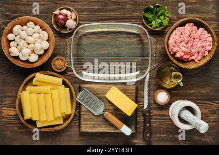 Gli ingredienti freschi sono disposti ordinatamente su un ripiano in legno per preparare un pasto di pasta. I componenti includono funghi, carne macinata, fogli di pasta, Foto Stock