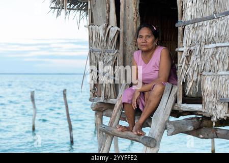 Ritratto di una donna della tribù bajau seduta all'ingresso di una casa di legno in un remoto villaggio sull'isola di muna vicino all'isola di sulawesi, indonesia, asia Foto Stock