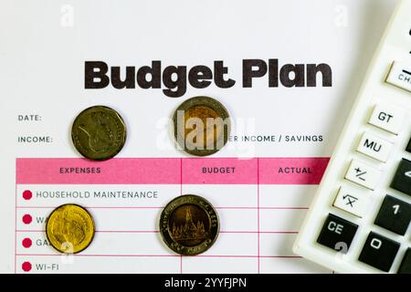 Pianificando un budget familiare con monete da baht thailandesi e calcolatrice. Tenere traccia delle spese e gestire le finanze in modo efficace. Foto Stock