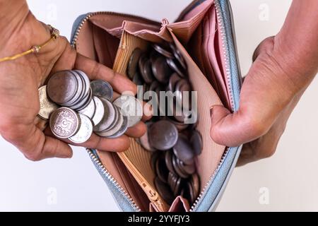 Mani con una borsa piena di monete in rupie indiane, evidenziando i concetti di risparmio e di finanza personale. Foto Stock