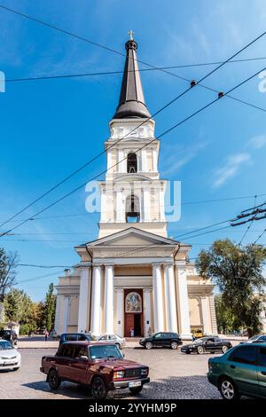 Una grande chiesa bianca con un alto campanile e un orologio sul lato. Il cielo è limpido e blu Foto Stock