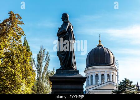 Una statua di una donna si trova di fronte a un grande edificio. La statua è circondata da alberi e il cielo è limpido e blu. Concetto di pace e tranqui Foto Stock