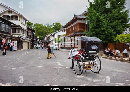 Miyajima, Giappone - 20 giugno 2024: I turisti esplorano la via dello shopping Miyajima Omotesandō, in arickshaw o jinrikisha, situata vicino all'Itsukushima Jinj Foto Stock