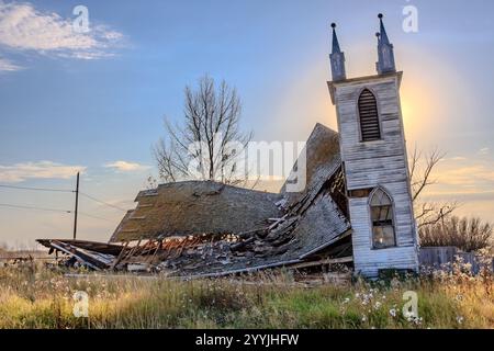 Una chiesa è stata distrutta e ora è un mucchio di macerie. Il sole splende sulle rovine, creando uno stato d'animo cupo e malinconico Foto Stock