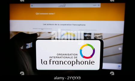 In questa foto, una persona ha in mano un cellulare con il logo dell'Organisation internationale de la Francophonie davanti alla pagina web. Foto Stock