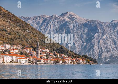 Vista panoramica di Perast, un affascinante villaggio costiero annidato sulla baia di Cattaro, con maestose montagne che si innalzano sullo sfondo Foto Stock