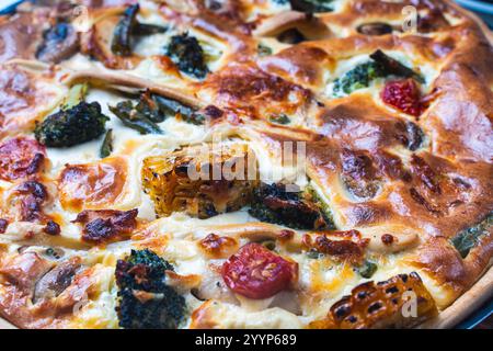 Sfondo, Quiche con broccoli, mais, pollo e pomodori è pronto per essere cotto in forno. Torta cruda su un tavolo bianco. Foto di alta qualità Foto Stock